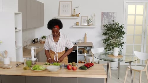 Woman Chopping Vegetables in Bright Kitchen