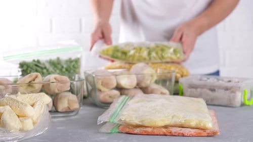 Stacking Bags of Various Frozen Foods on Countertop