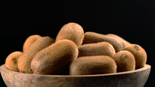 Fresh Kiwis Rotating in Rustic Wooden Bowl