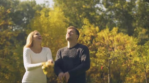 Happy Couple Tossing Autumn Leaves in Park