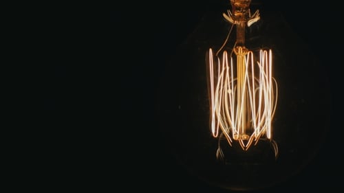 Vintage Edison Lamp Lights Up Continuously. On a Black Background, Slightly Swaying