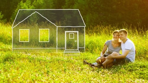 Young Happy Couple Sitting on Green Grass in Park and Dreaming About They Own House. Mortgage