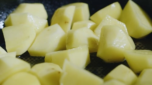 Diced Potatoes Fried in a Pan. Under It Boils Sunflower Oil. Junk Food