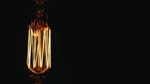 Oblong Vintage Lamp Edison. Slowly Turn on a Black Background. Near the Free Space for Titles