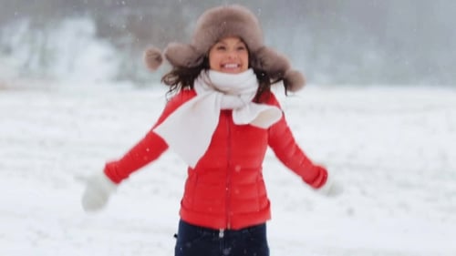 Smiling Woman Wearing Winter Clothes Bounces in Snow