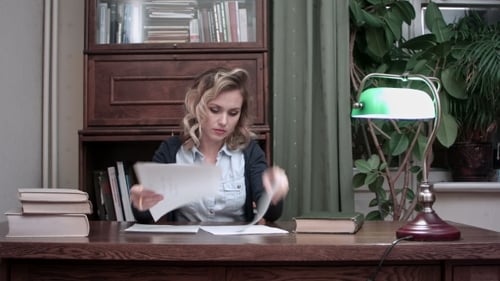 Young Woman Going Through Papers and Making Notes