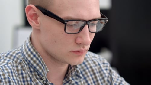 Young Man in Glasses Working in the Office
