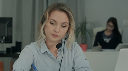 Callcenter-Mitarbeiter machen Notizen, während sie mit dem Kunden sprechen