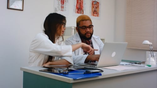 Doctors Collaborating with Laptop in Hospital Office