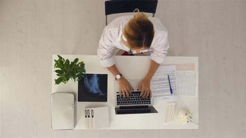 Young Beautiful Female Doctor Working on Laptop at the Office