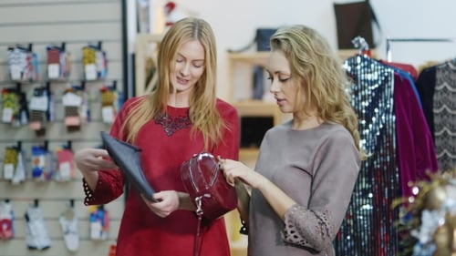 Two Stylish Lady in a Shop of Accessories and Clothes Are Choosing Handbags. Successful Shopping