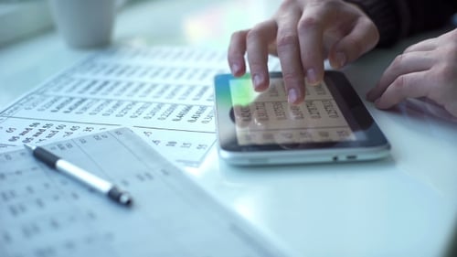 Adult Using Tablet on Desk with Financial Documents