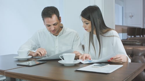 Two Business Partners Discussing Work and Smiling While Sitting in Cafe