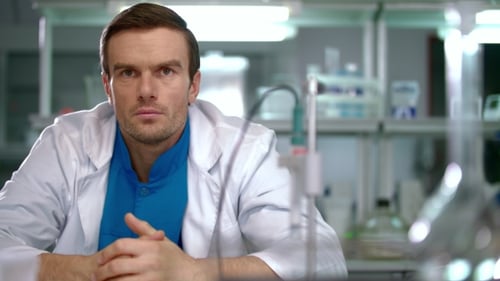Man in Lab Coat Sitting in Laboratory