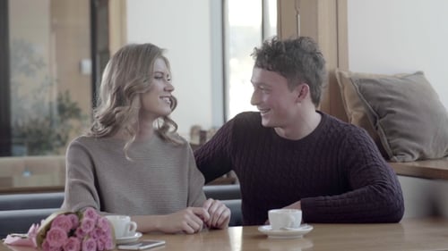Verliebtes Paar in einem Café: Ein Mann schenkt am Valentinstag Geschenke.