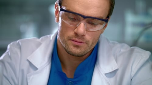 Close Up Scientist Pours Liquid into Beaker