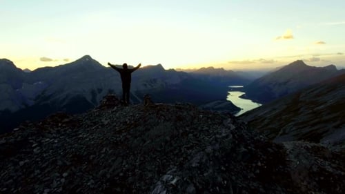 Woman Celebrating Reaching Peak of a Hike in the Mountains at Sunset