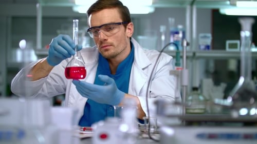 Man in Lab Coat Taking Notes in Laboratory