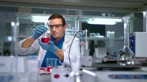 Scientist Examining Red Liquid in Flask in Lab
