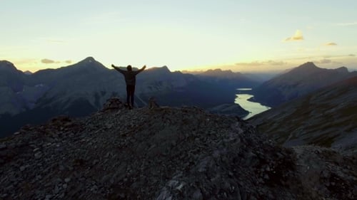 Woman Celebrating Reaching Peak of a Hike in the Mountains at Sunset