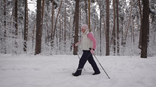 Senior Woman Nordic Walking in Winter Forest