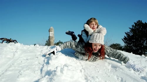 Happy Mother and Son Moves Down on Sled, Family Sleigh Ride Through the Snow