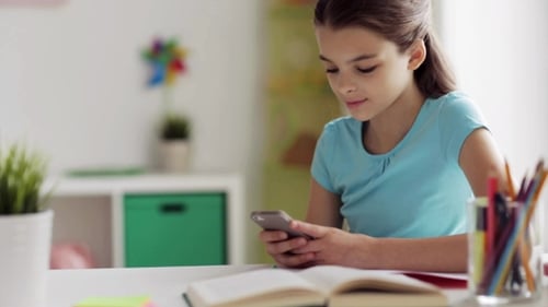 Girl Uses Smartphone at Desk with Open Book