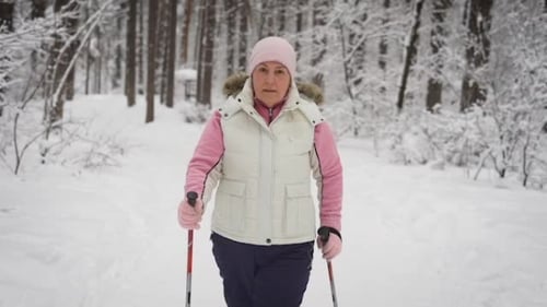 The Elderly Woman Spends Leisure-time in the Wood. Winter Forest. The Woman Supports the Level of