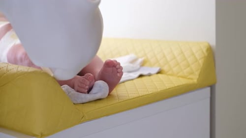 Close Up of Mom Changing Diapers for Baby She is Lying in the Crib
