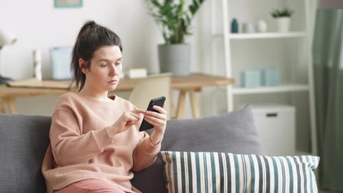 Woman Using Smartphone Relaxing on Couch at Home