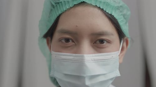 Nahaufnahme einer asiatischen Krankenschwester mit Gesichtsmaske in medizinischer Schutzuniform, die im Krankenhaus arbeitet.