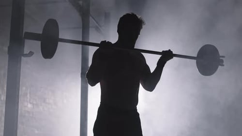 Strong Man Doing Front Squats in Smoky Gym