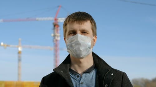 Man Wearing Protective Face Mask Near Construction Cranes