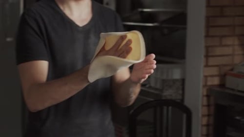 Young Adult Shaping and Tossing Pizza Dough