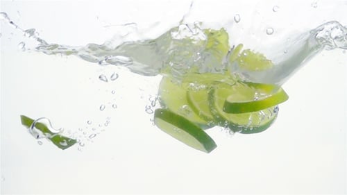 Fresh Lime Slices Falling into Water