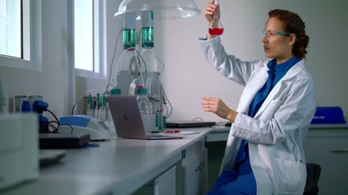 Woman Scientist Examining Red Liquid in Laboratory