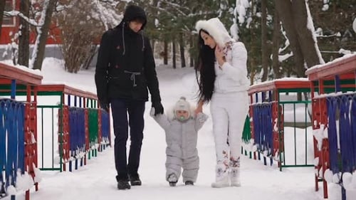 Father and Mother with Her Son Walk Down an Alley in a Winter Park