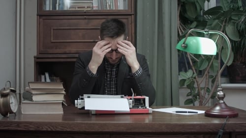 Man with Typewriter Contemplates Writing at Desk