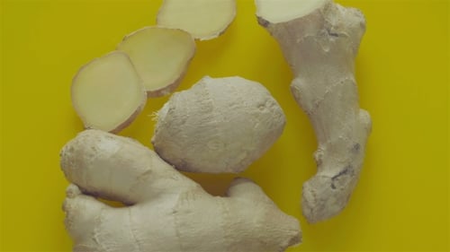 Fresh Ginger Root and Slices on Yellow Background