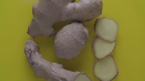 Whole and Sliced Ginger Root on Yellow Background
