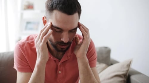 Man Rubbing Temples While Sitting on Couch