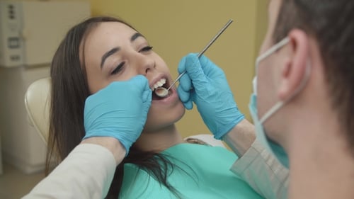 The Dentist Examines a Female Patient in the Dental Office.
