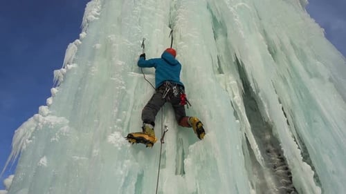 Ice Climber Ascending Frozen Waterfall in Winter