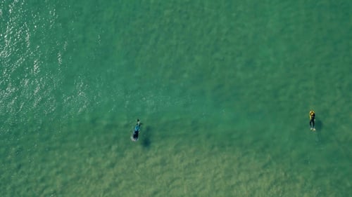 Aerial View of Surfers Riding Green Ocean Waves