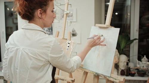 Female Painter Drawing in Art Studio Using Easel