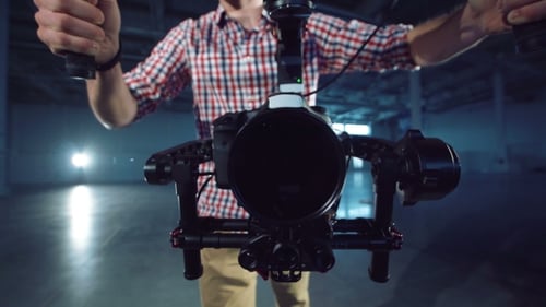 Man Demonstrates Camera Stabilizer Equipment in Empty Warehouse