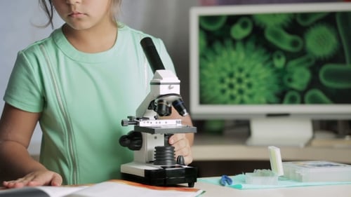 Young Girl Scientist Looking Into Microscope