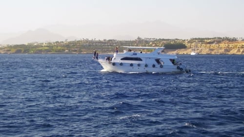 Ausflugsboot schwimmt auf den Wellen des Roten Meeres vor dem Hintergrund der Küste und der Strände in Ägypten