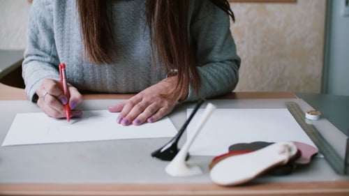 Craftswoman Drawing Shoe Pattern at Desk