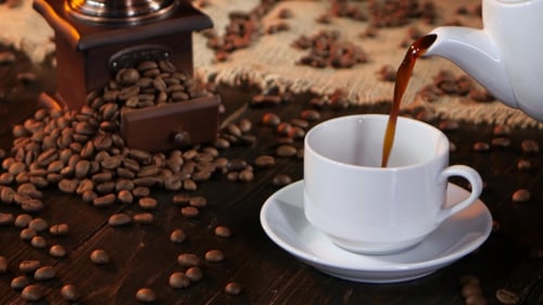 Coffee Being Poured into Cup With Coffee Beans